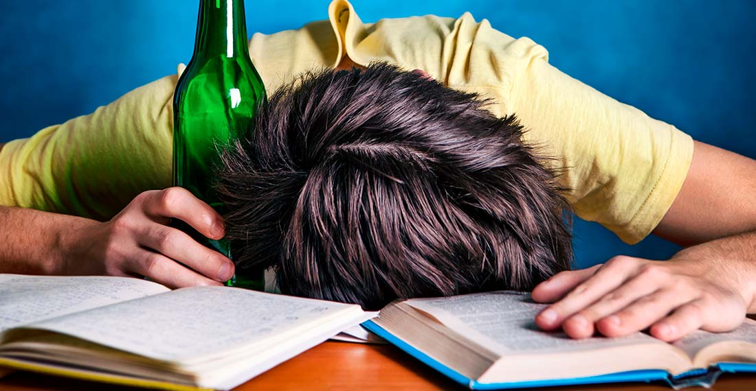 пьяный мужчина спит за столом с книгами